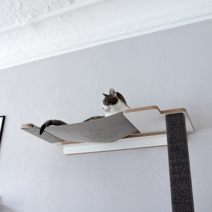 Eine Katze entspannt auf der Hängematte eines Kletter-Kratzstammes.